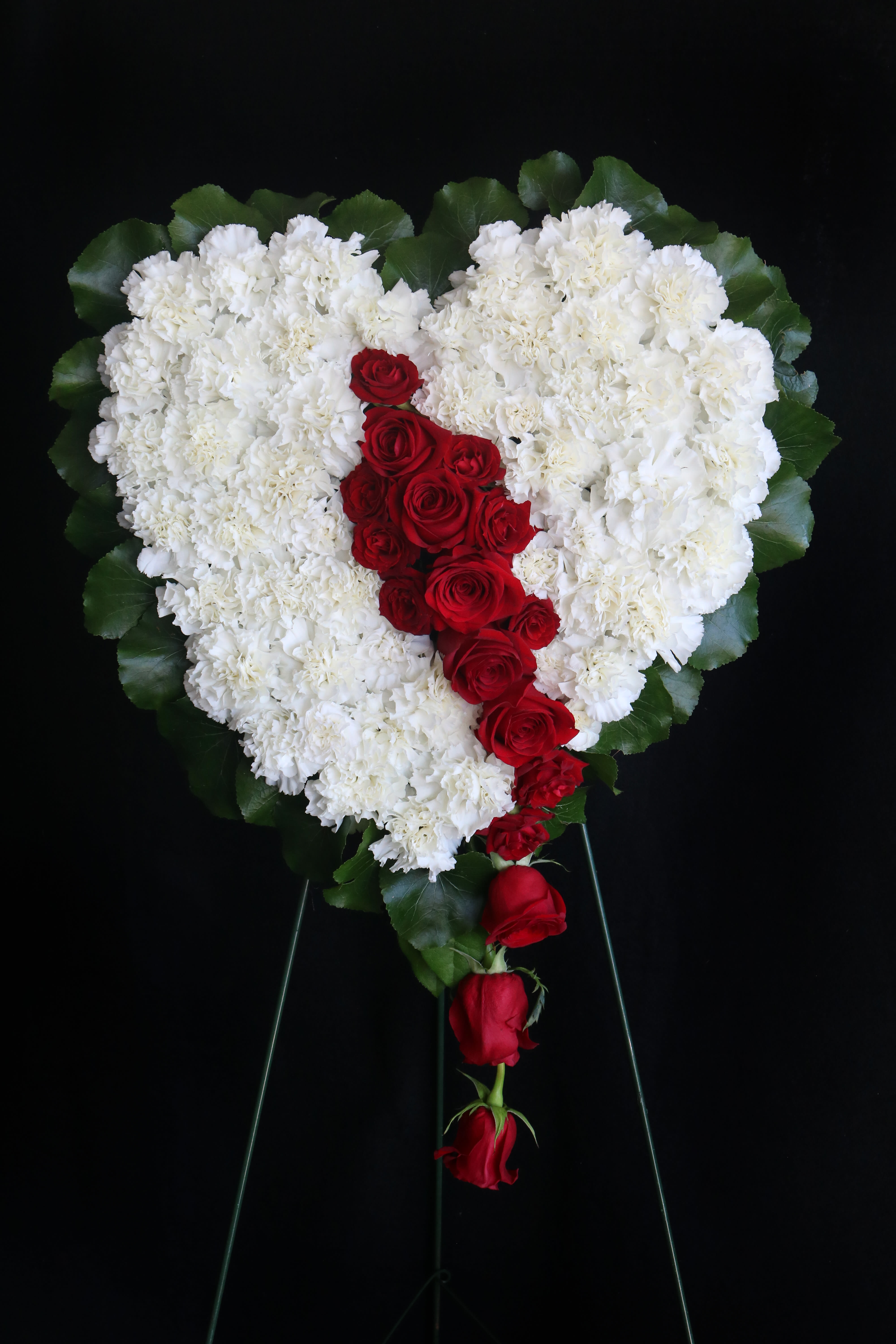Heart-shaped white floral spray with red roses down the center