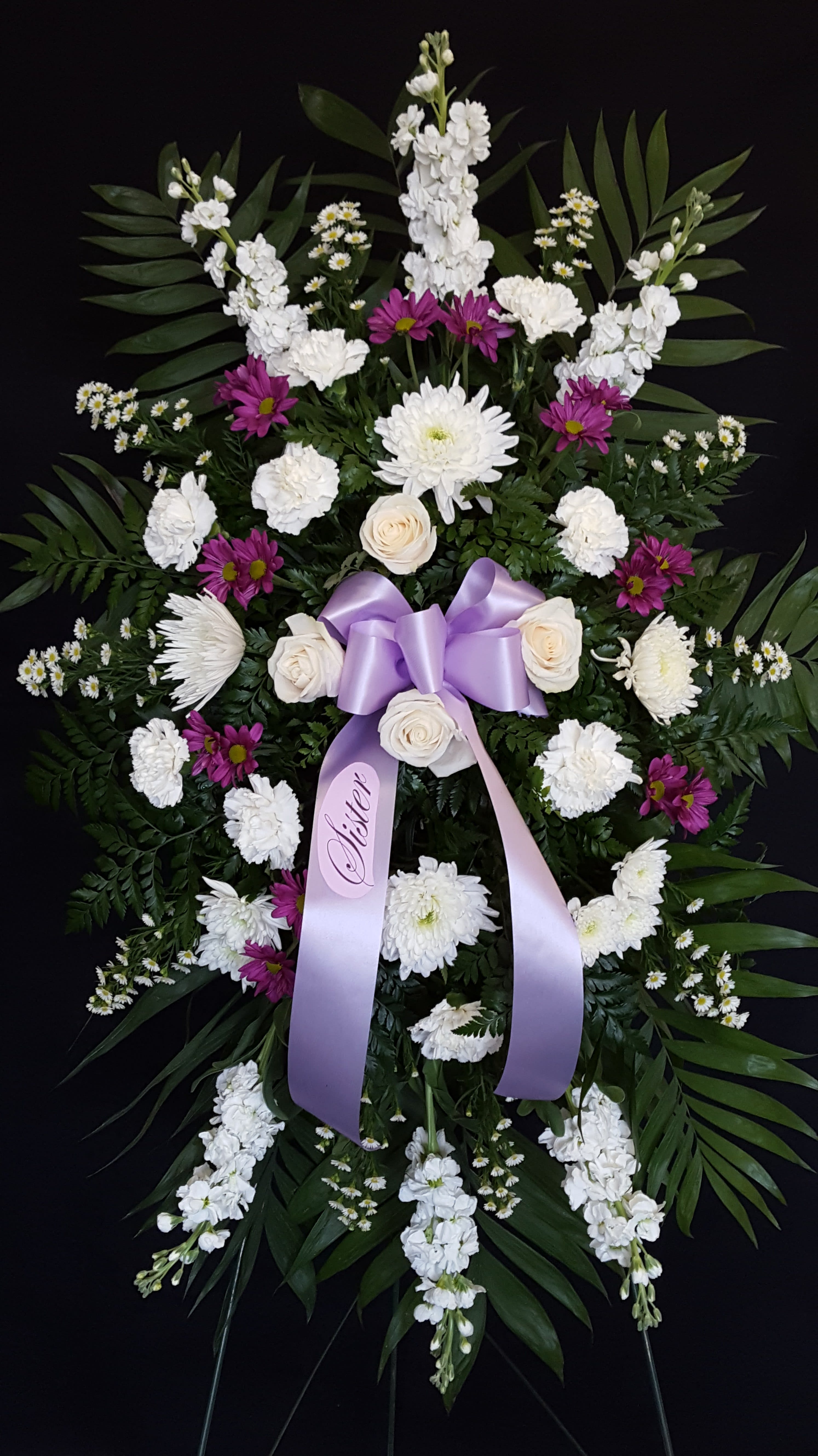 Standing floral spray with white and purple flowers and a lavender ribbon