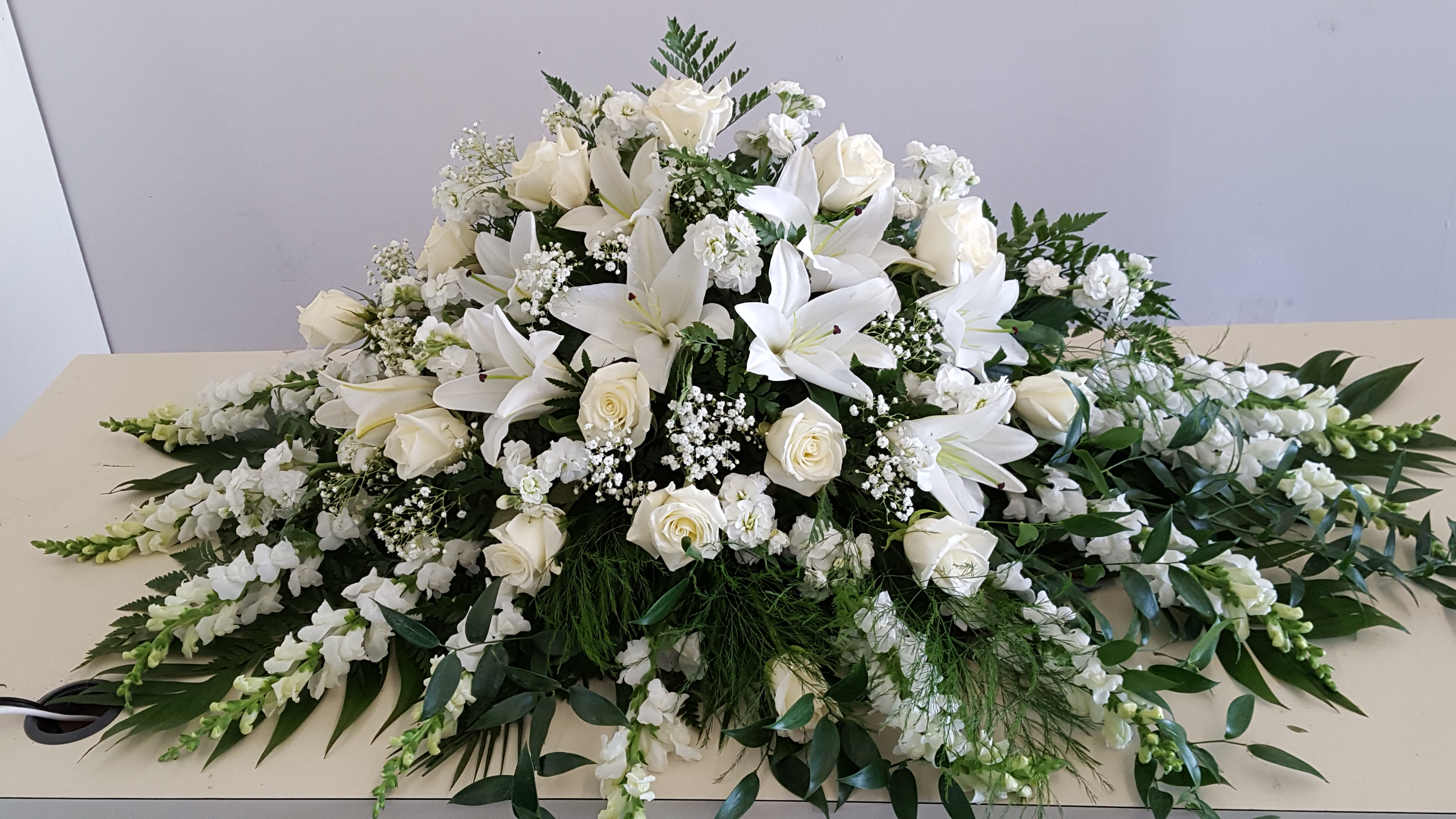 Large white floral spray with lilies and roses on a table