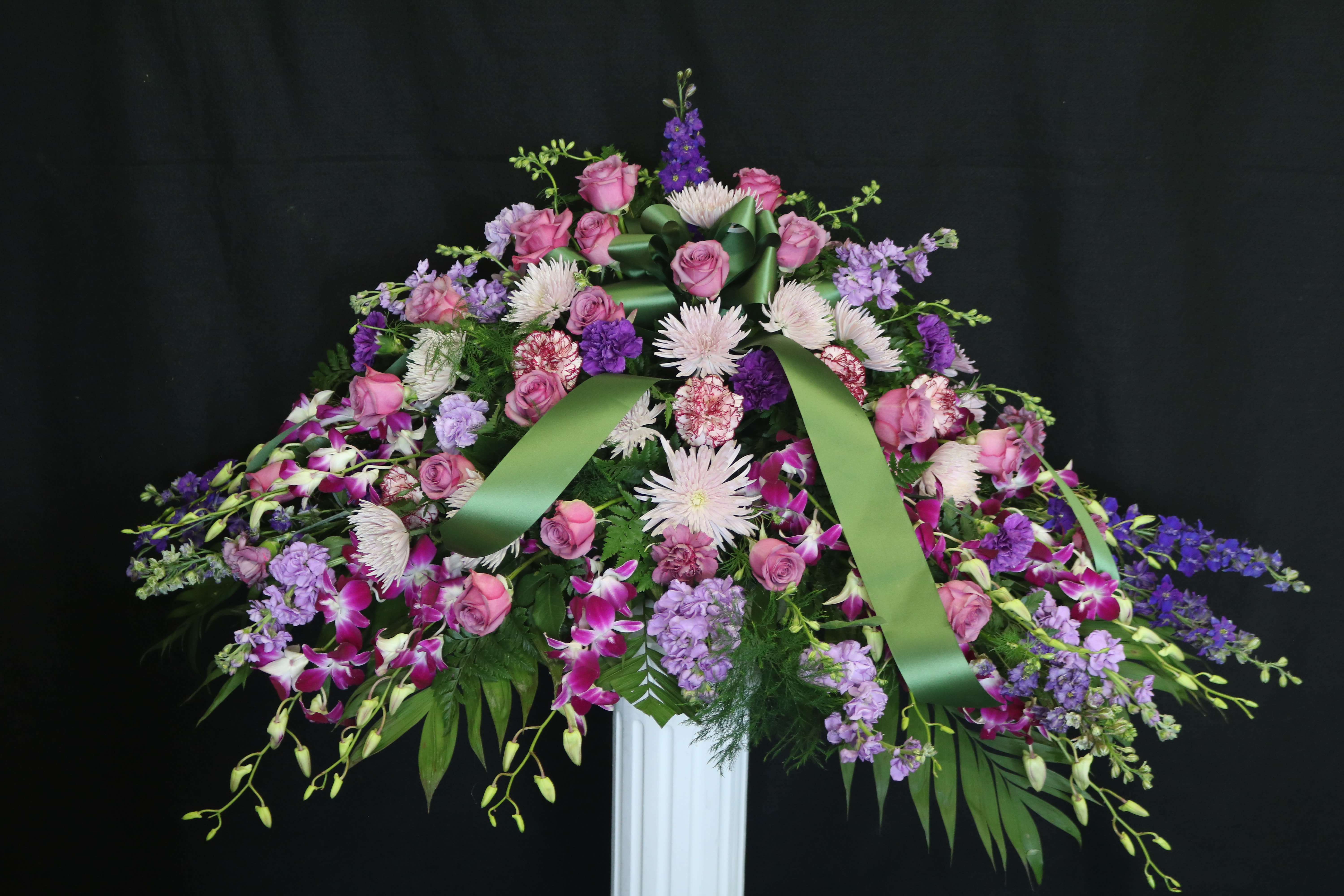 Large floral spray with pink roses and purple flowers on a stand