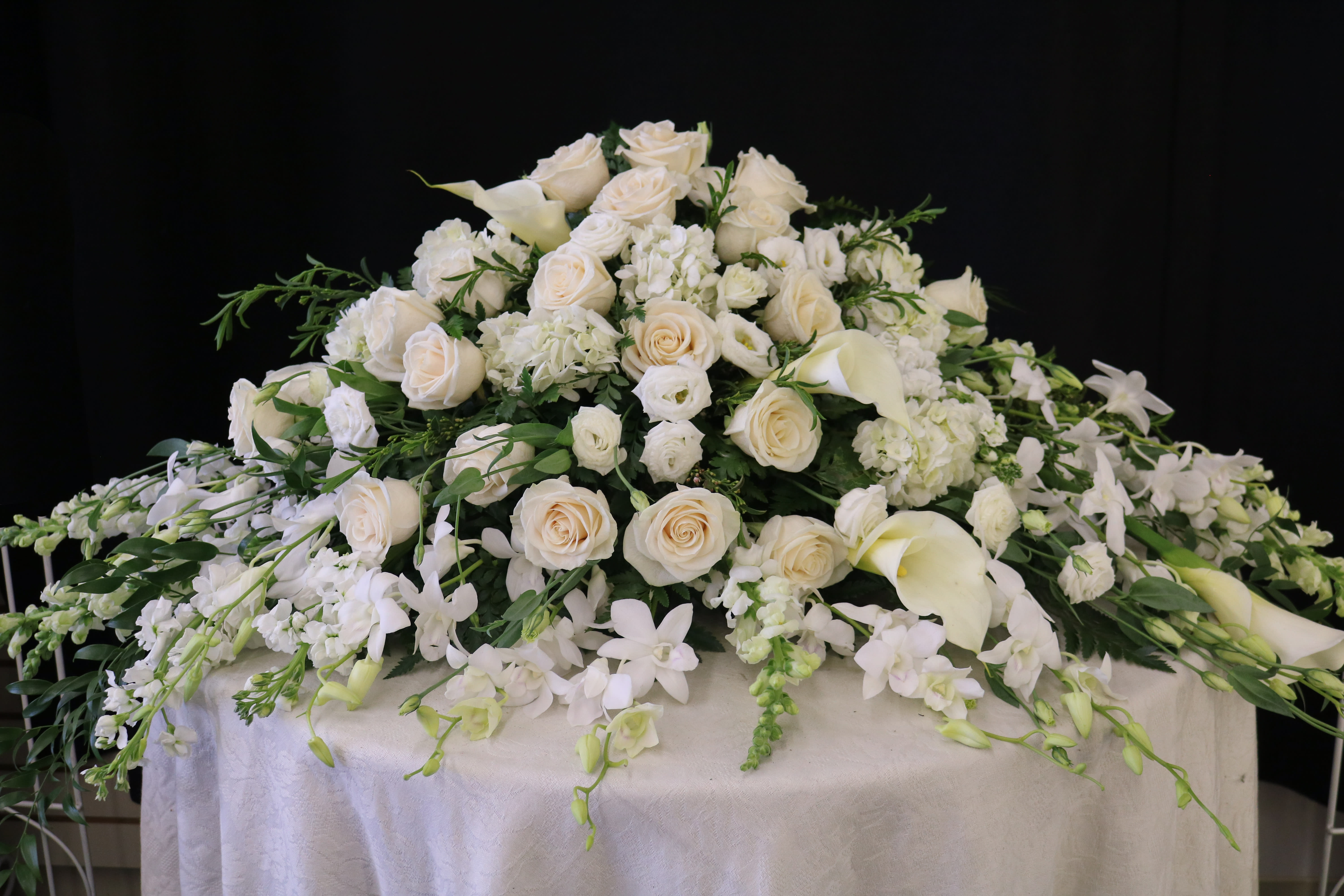 Large white floral casket spray with roses and calla lilies