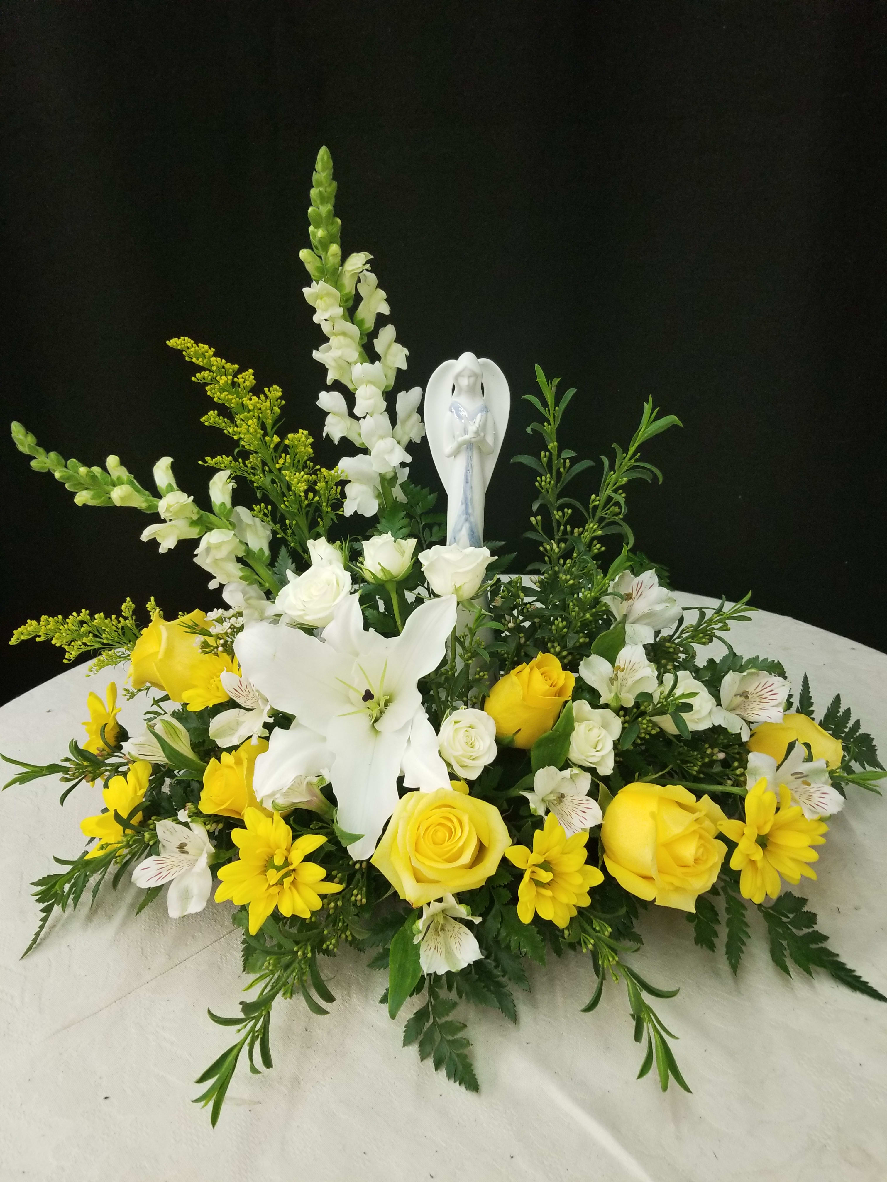 Yellow and white floral arrangement with a small angel figurine