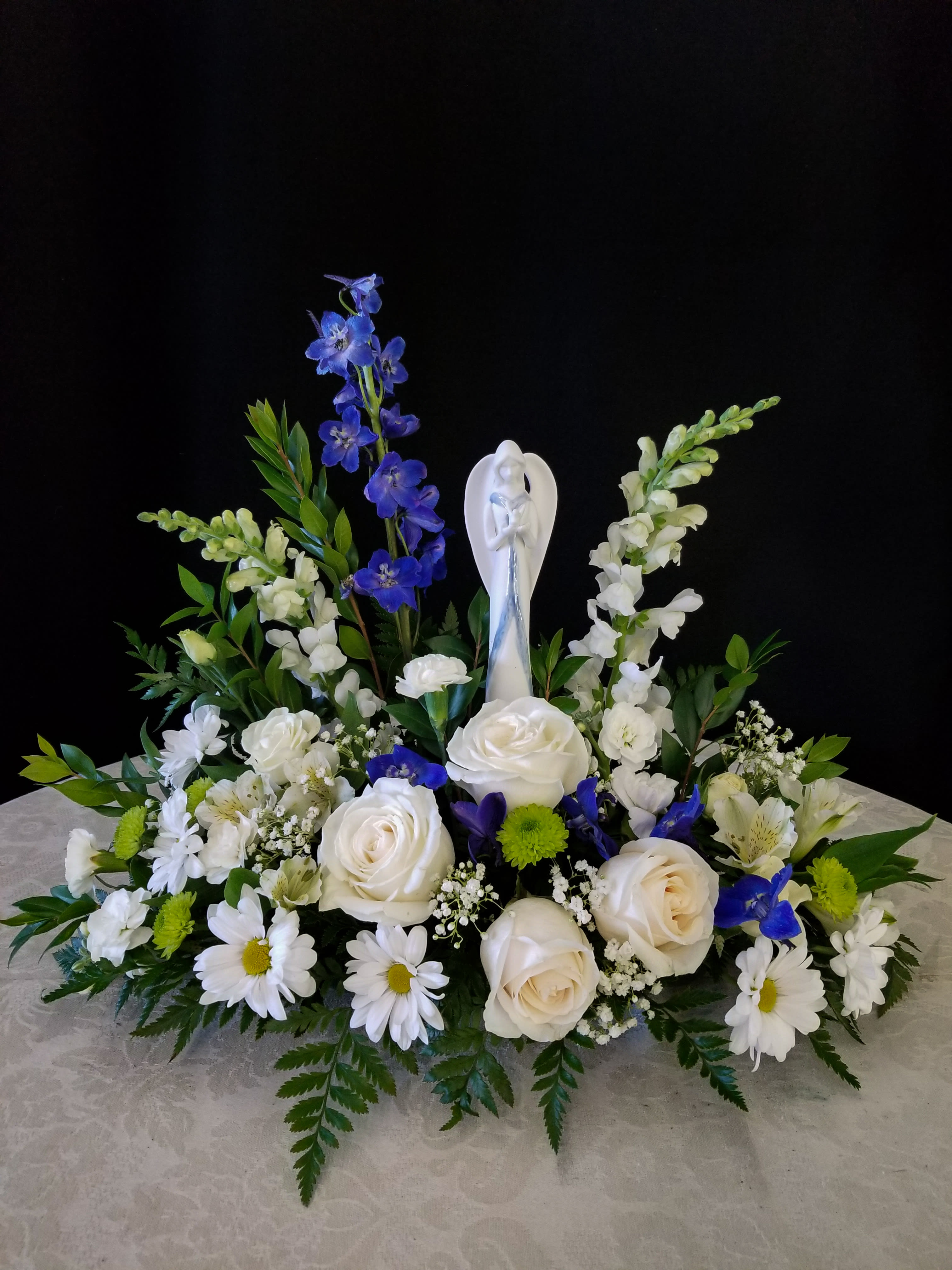 White and blue floral arrangement with a central angel figurine