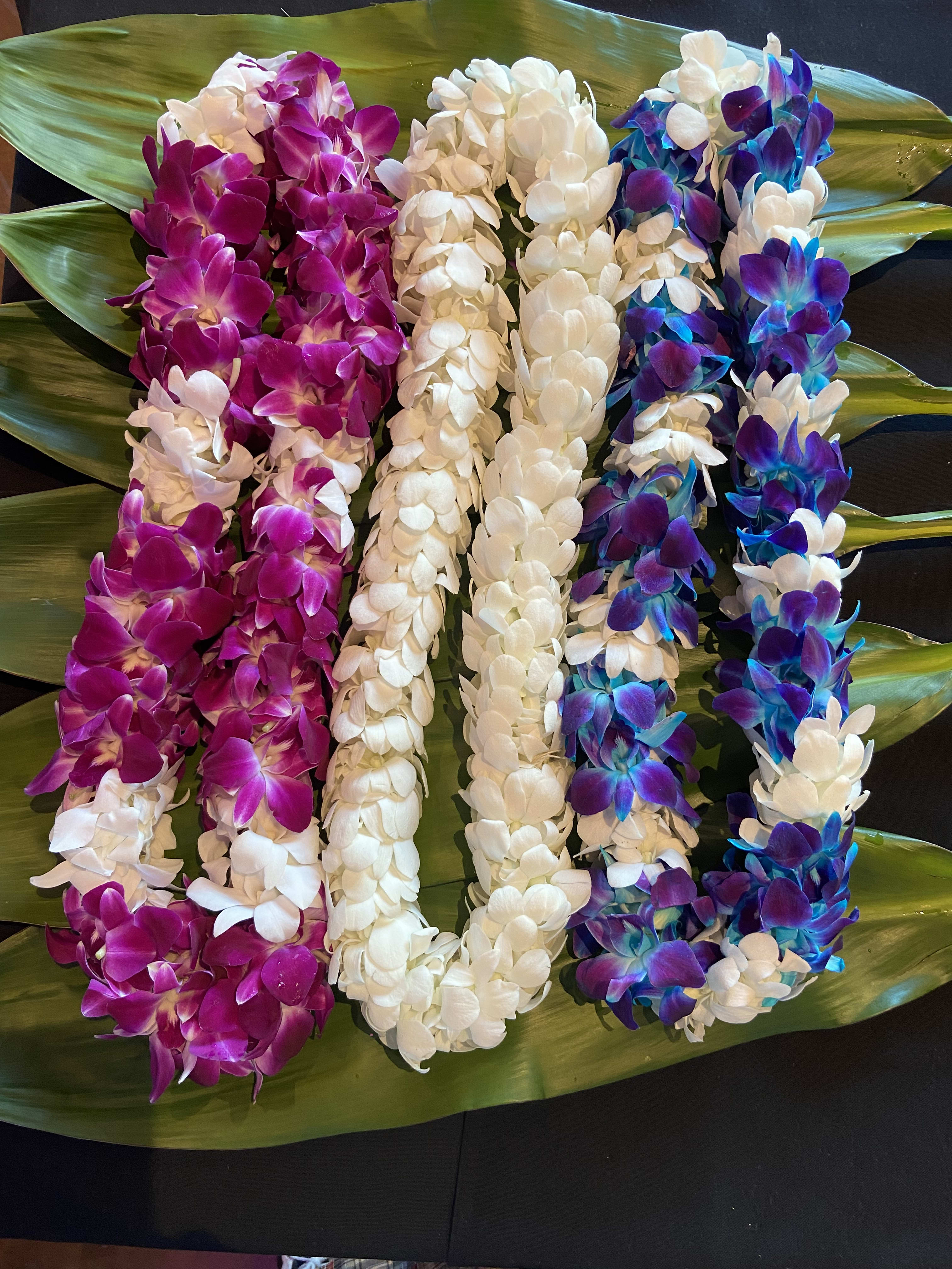 Colorful orchid leis laid on large green leaves