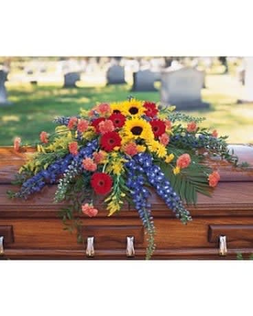 Vibrant Summer Casket Spray - Pay tribute to a colorful, rich life with this casket spray of summer flowers. One casket spray arrives decorated with radiating stalks of hybrid blue delphinium and clusters of red gerberas, yellow sunflowers and orange carnations. Approximately 47" W x 32" H As Shown : TF202-1