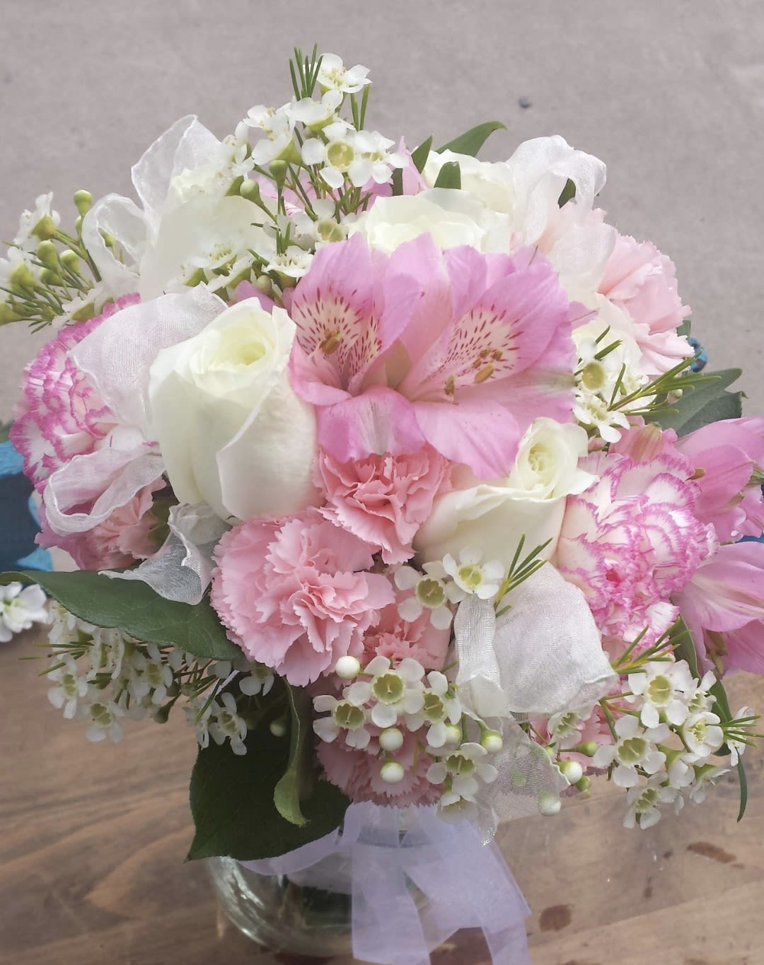 Pink and white bouquet in a clear glass vase with ribbon
