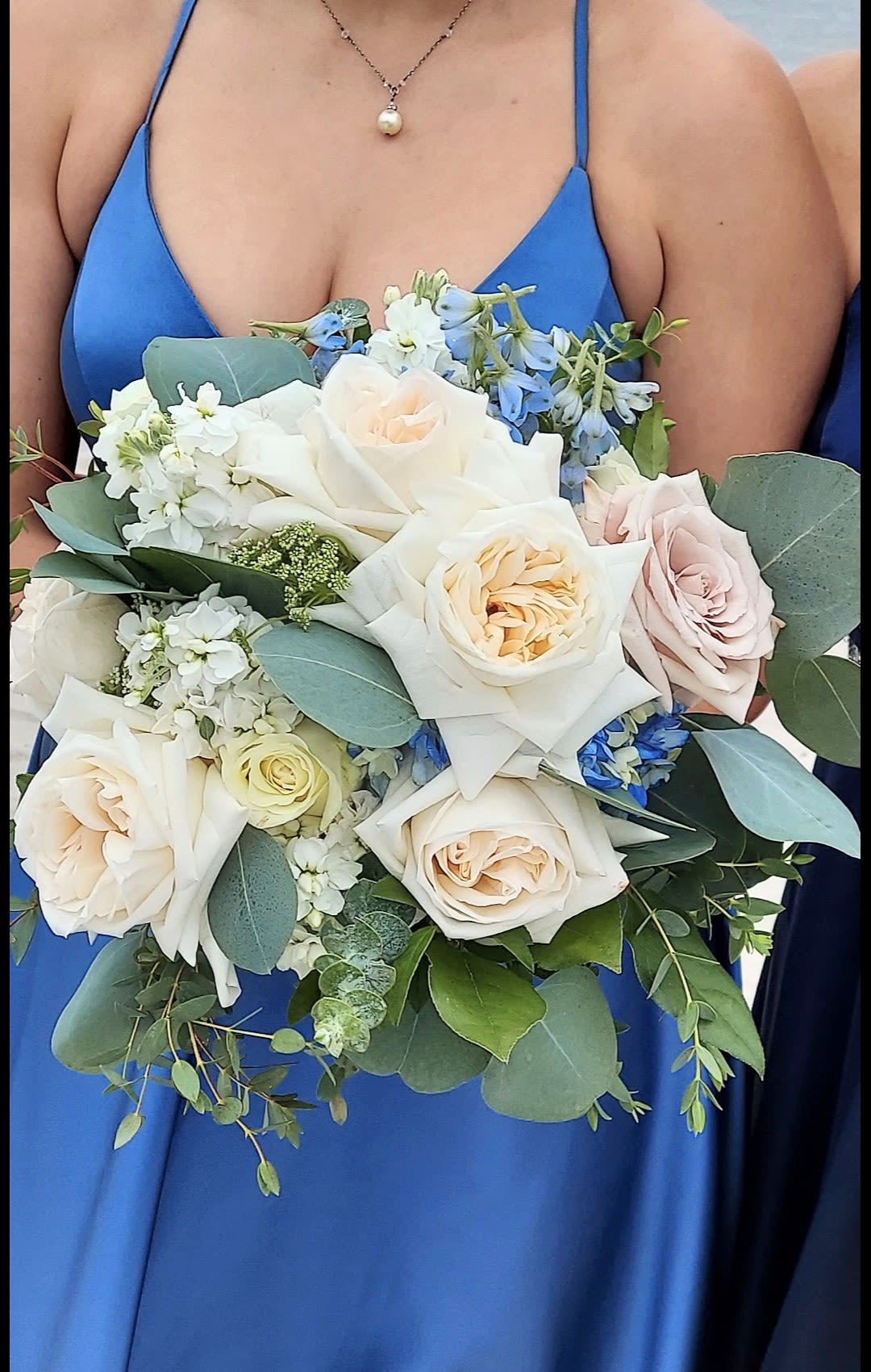Woman holding a bouquet of pale roses and blue flowers