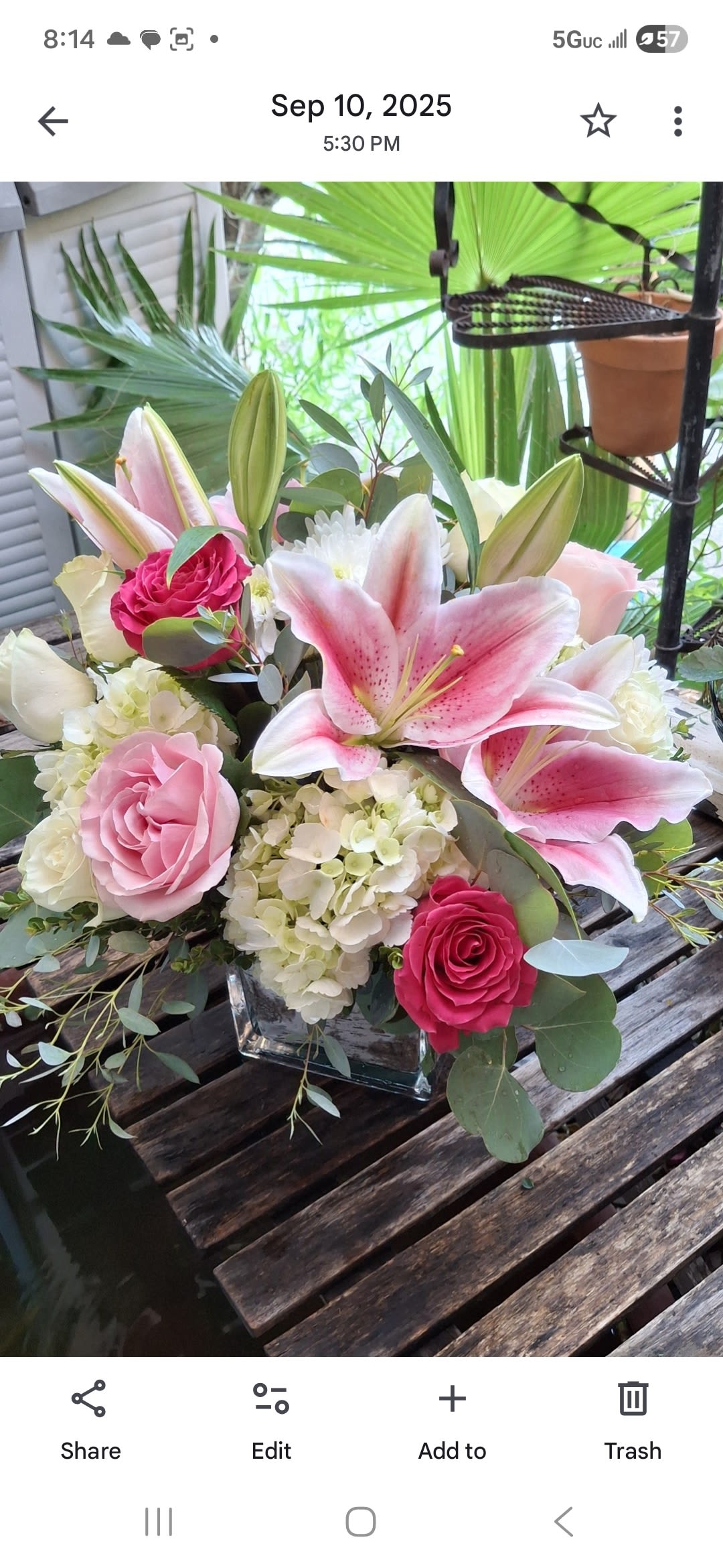 Pink lilies and roses arranged in a square glass vase