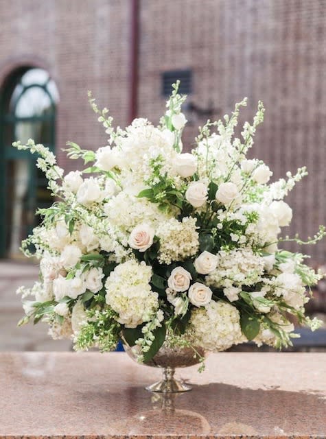 Large white floral arrangement in a silver pedestal bowl
