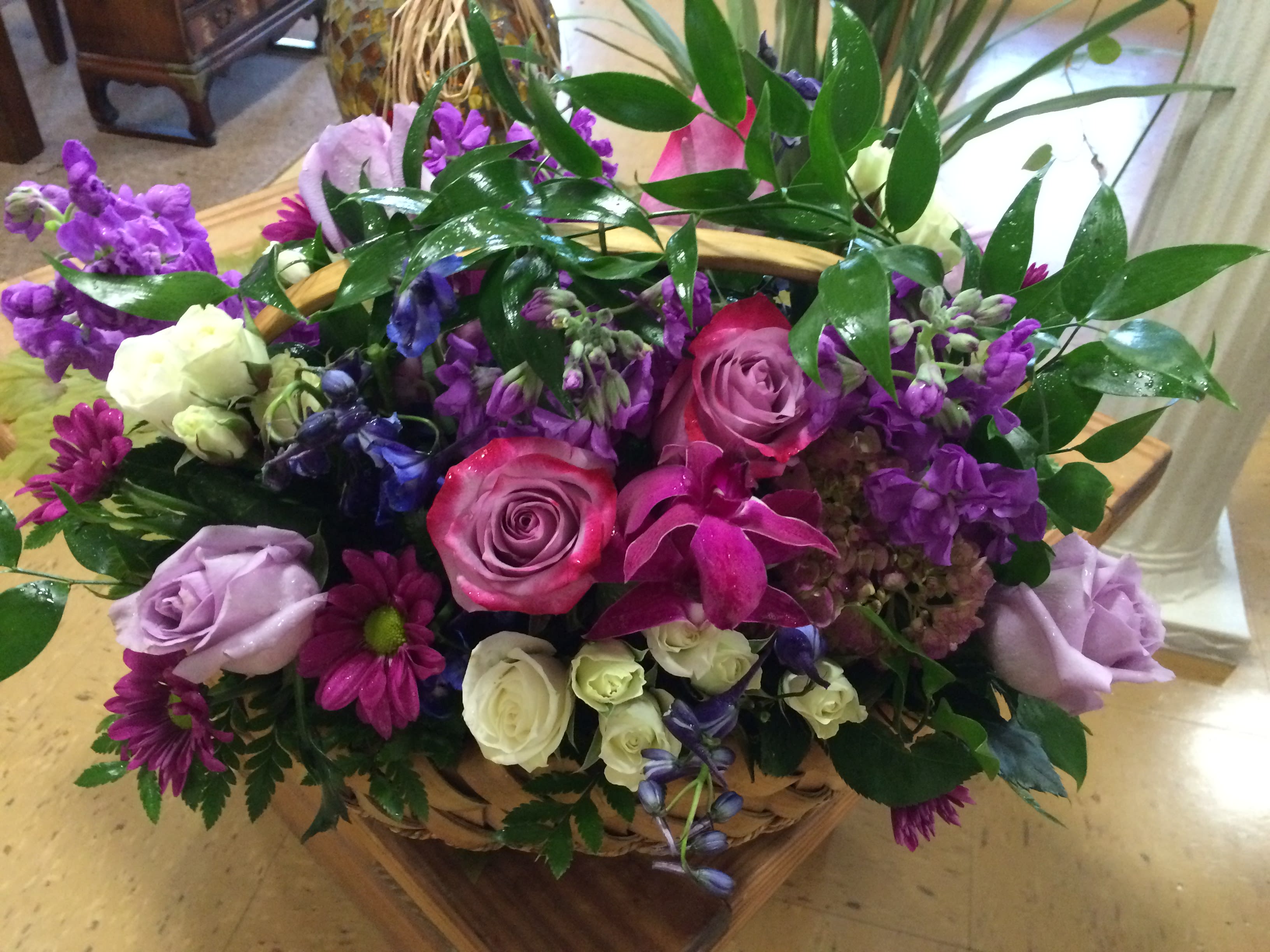 Basket arrangement of pink, purple, and white flowers with glossy greenery