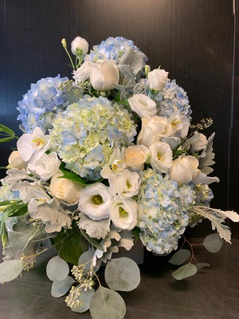 Blue hydrangeas and white roses arranged with silver foliage