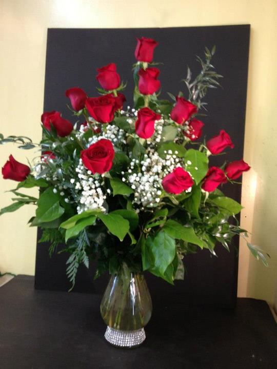 Red roses arranged in a clear glass vase with baby's breath