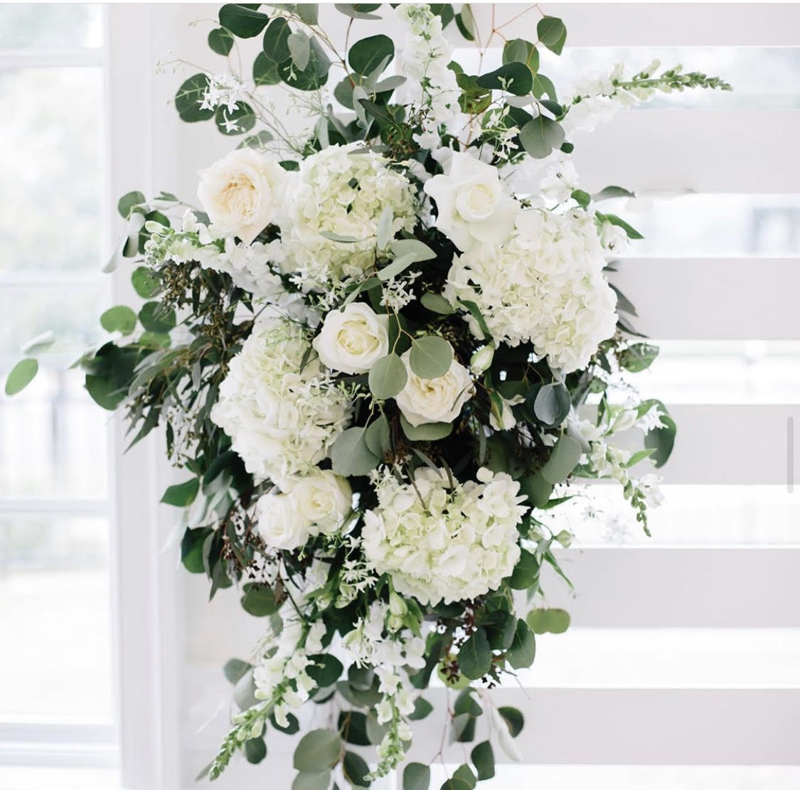 Tall white floral arrangement with roses and hydrangeas