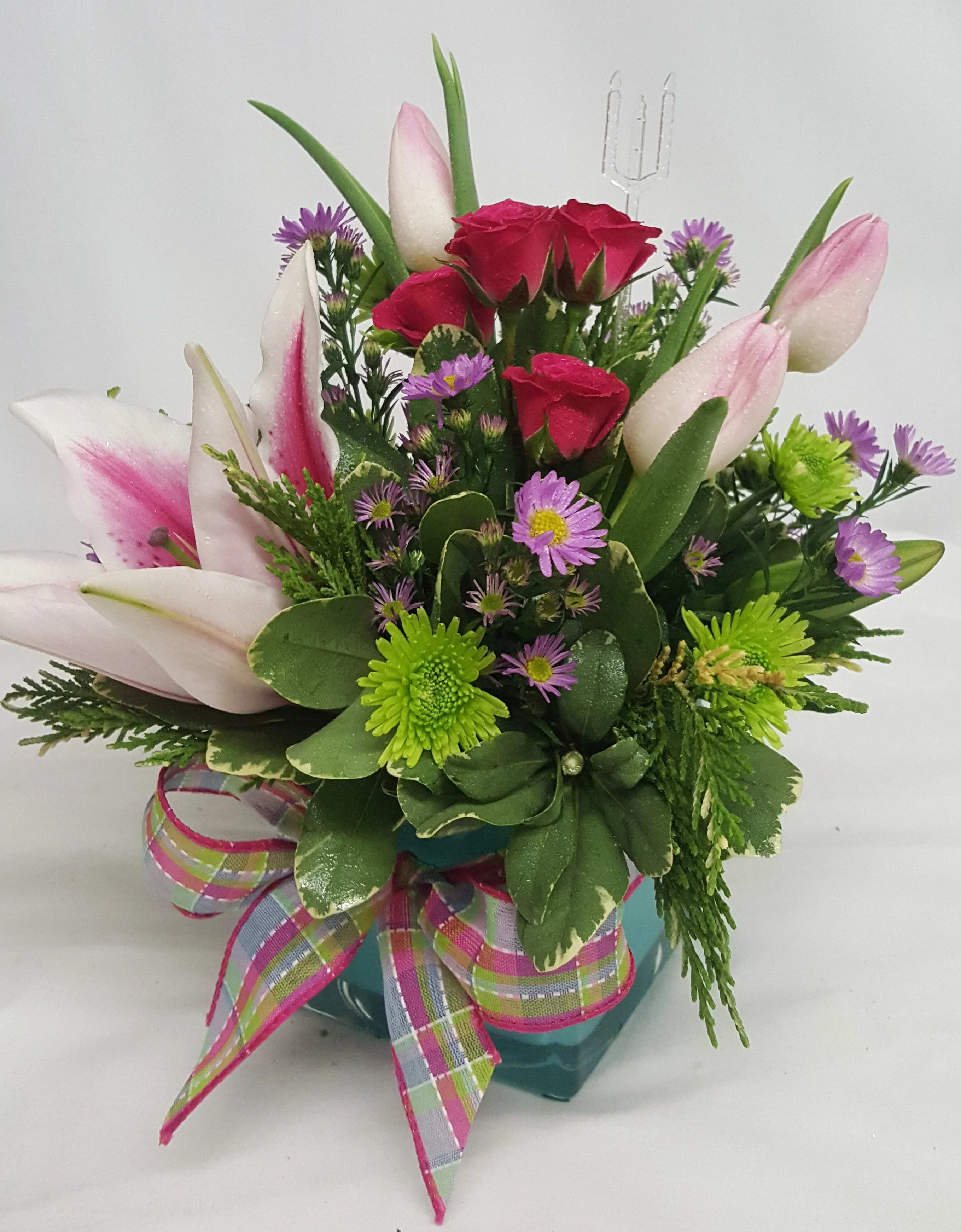 Pink tulips and red roses in a teal vase with a plaid ribbon