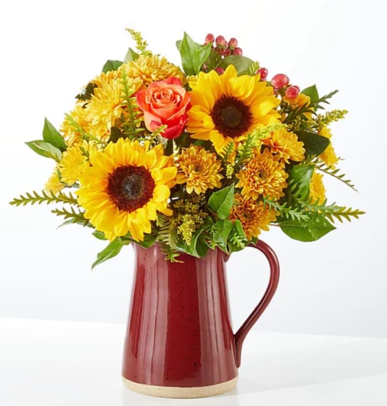 Sunflower and rose bouquet in a red ceramic pitcher