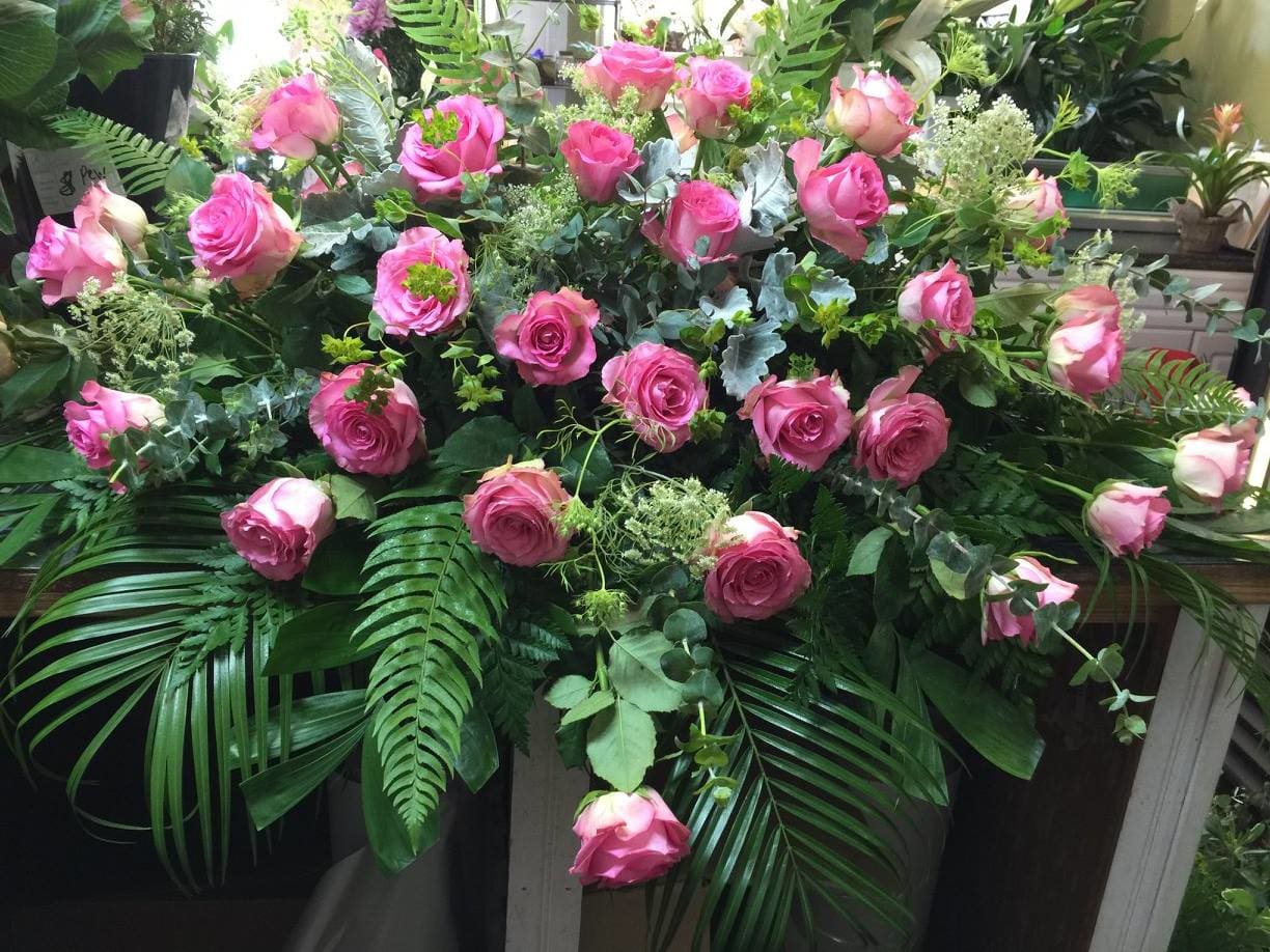 Large arrangement of pink roses with lush greenery