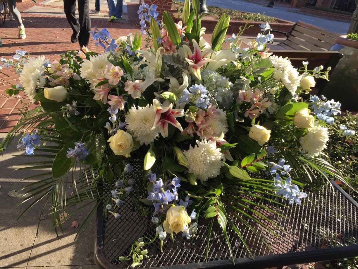 Large mixed floral arrangement with white lilies, roses, and blue flowers