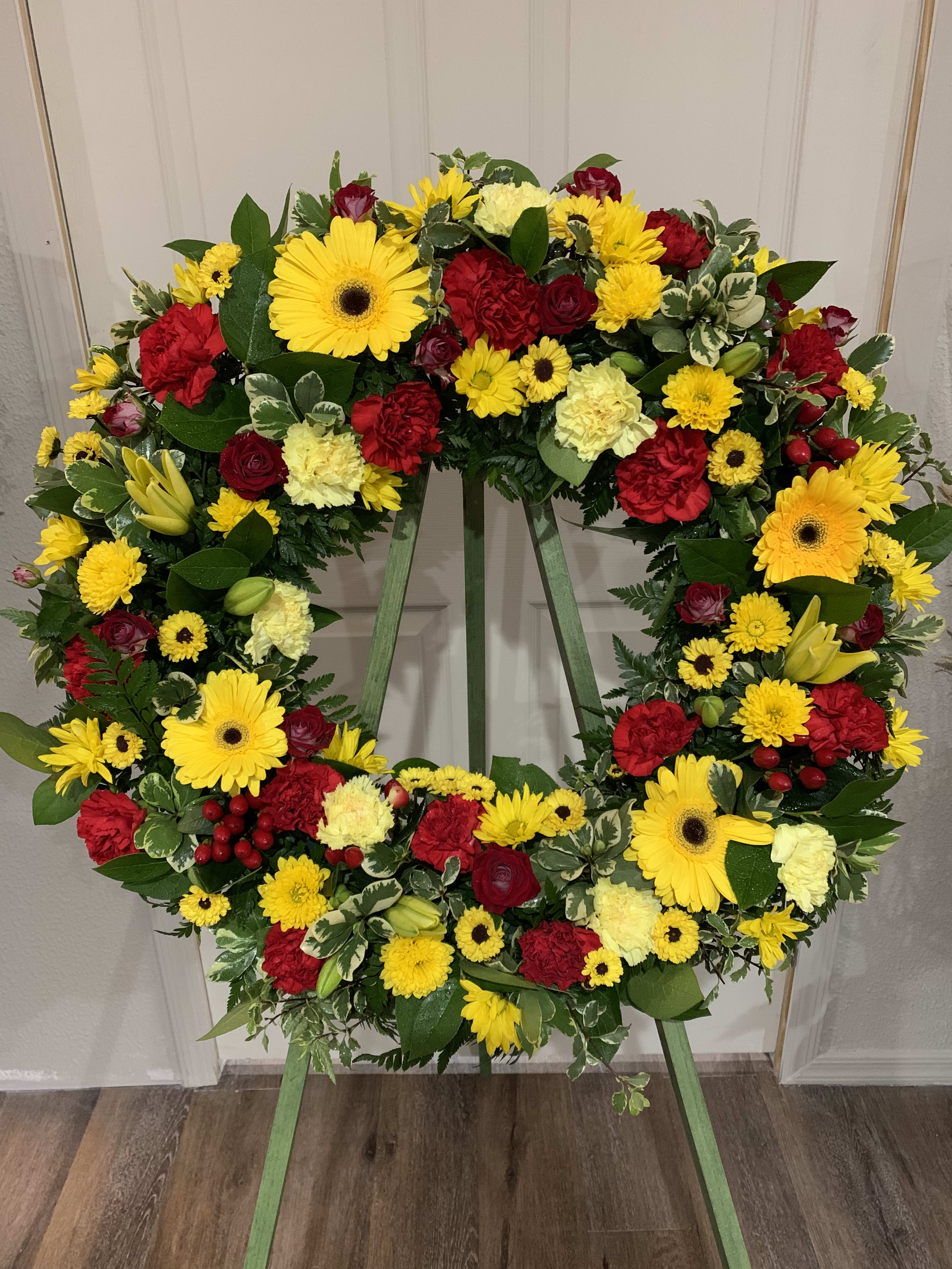 Large circular wreath of red and yellow flowers on a stand