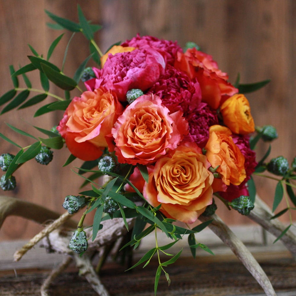 Bouquet of orange and pink roses with greenery