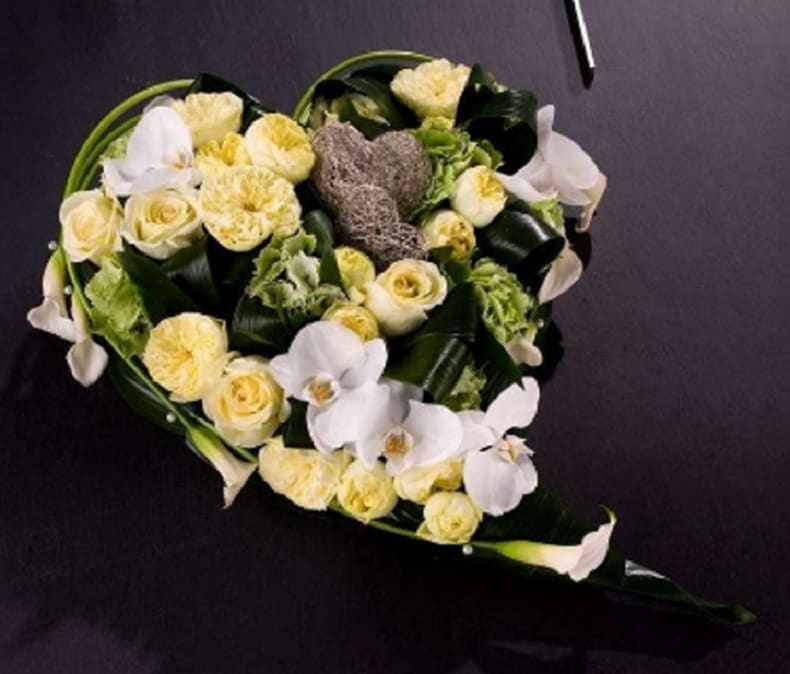 Heart-shaped bouquet of white and pale yellow flowers on a dark background