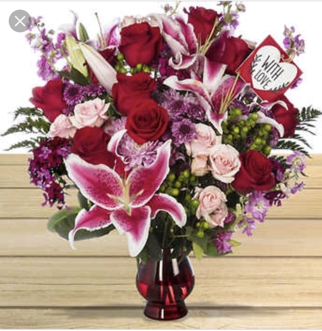 Red roses and pink lilies in a red glass vase with a heart sign