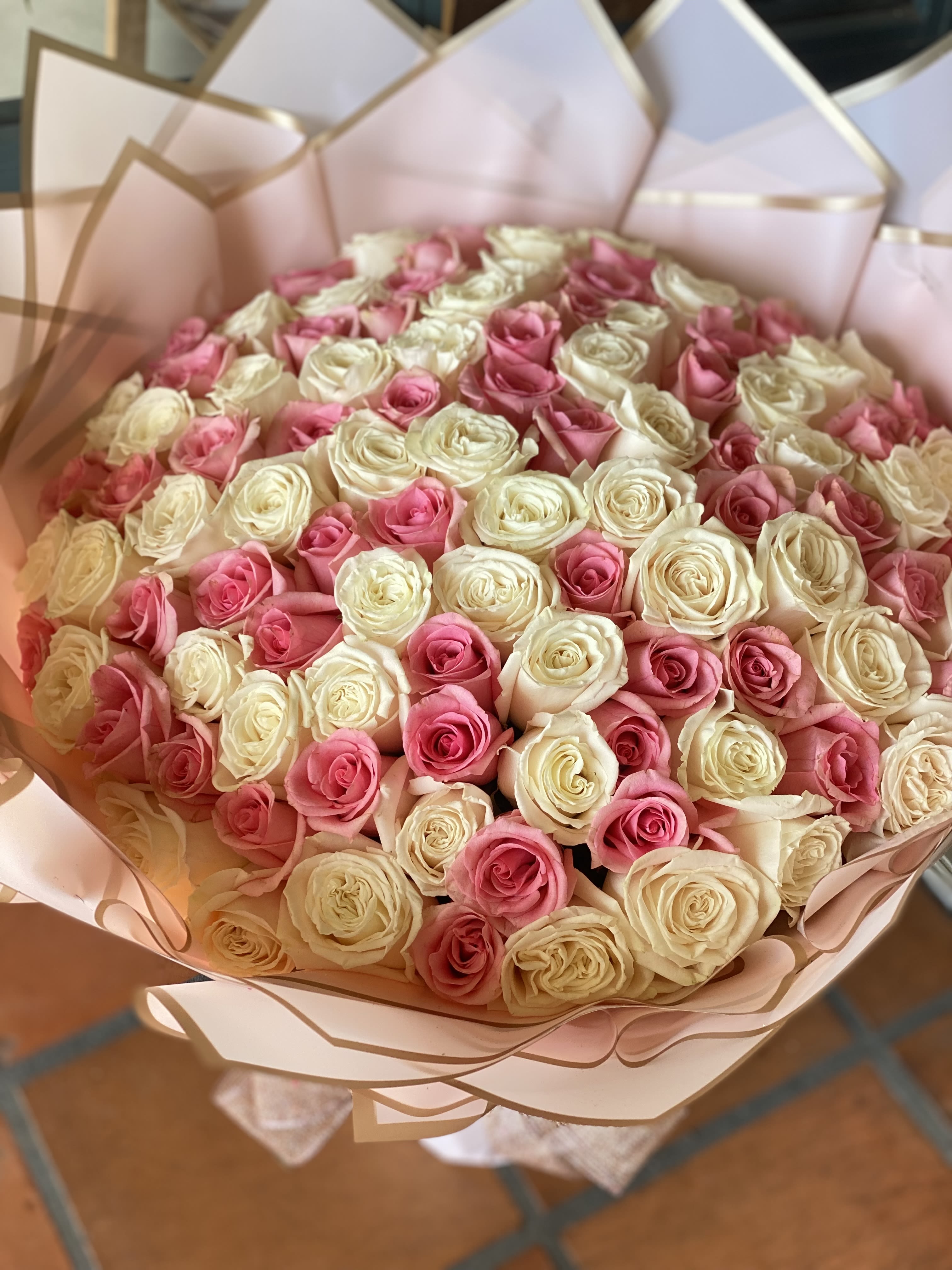 Bouquet of pink and cream roses wrapped in pale pink paper