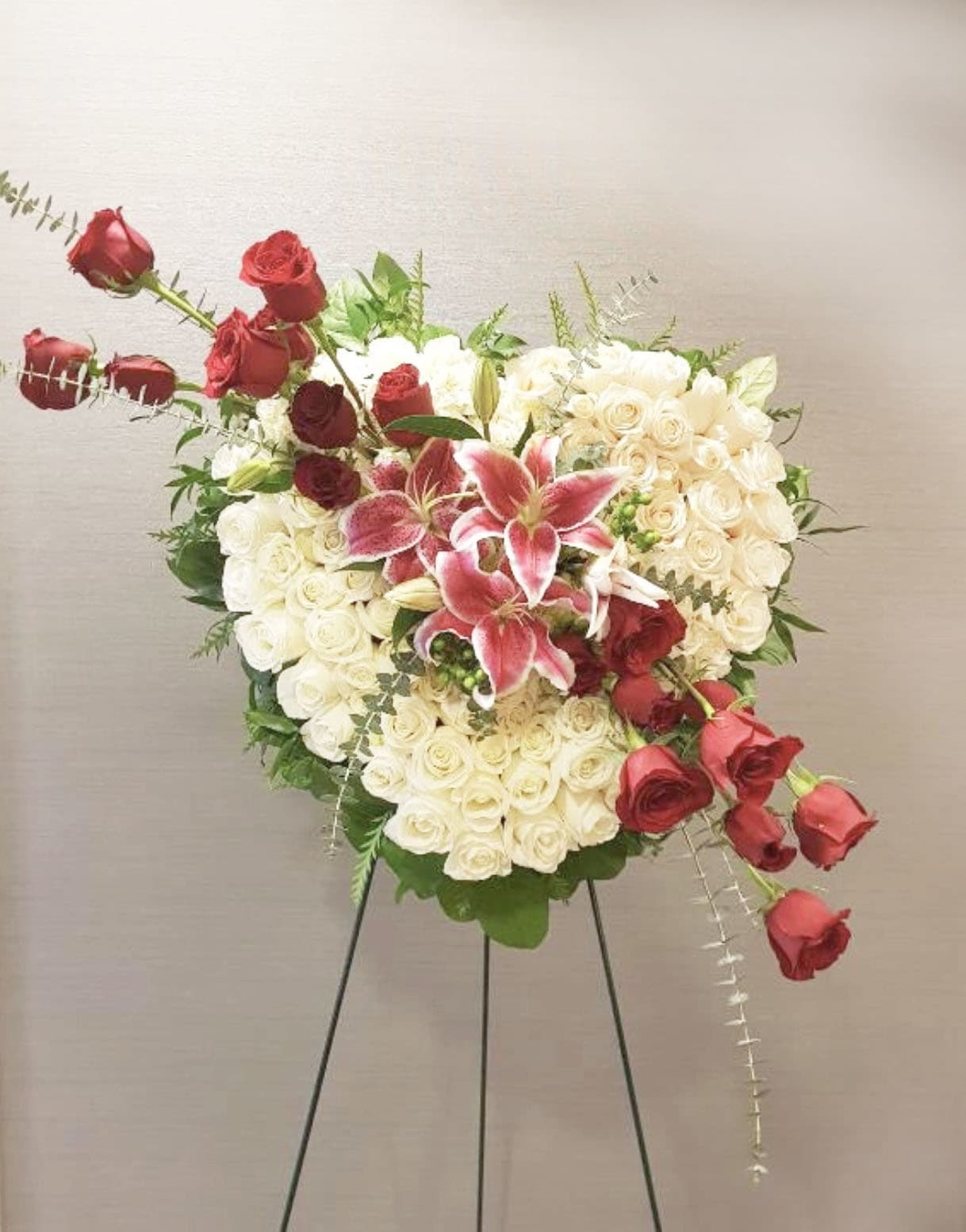 Heart-shaped rose arrangement with pink lilies on a stand
