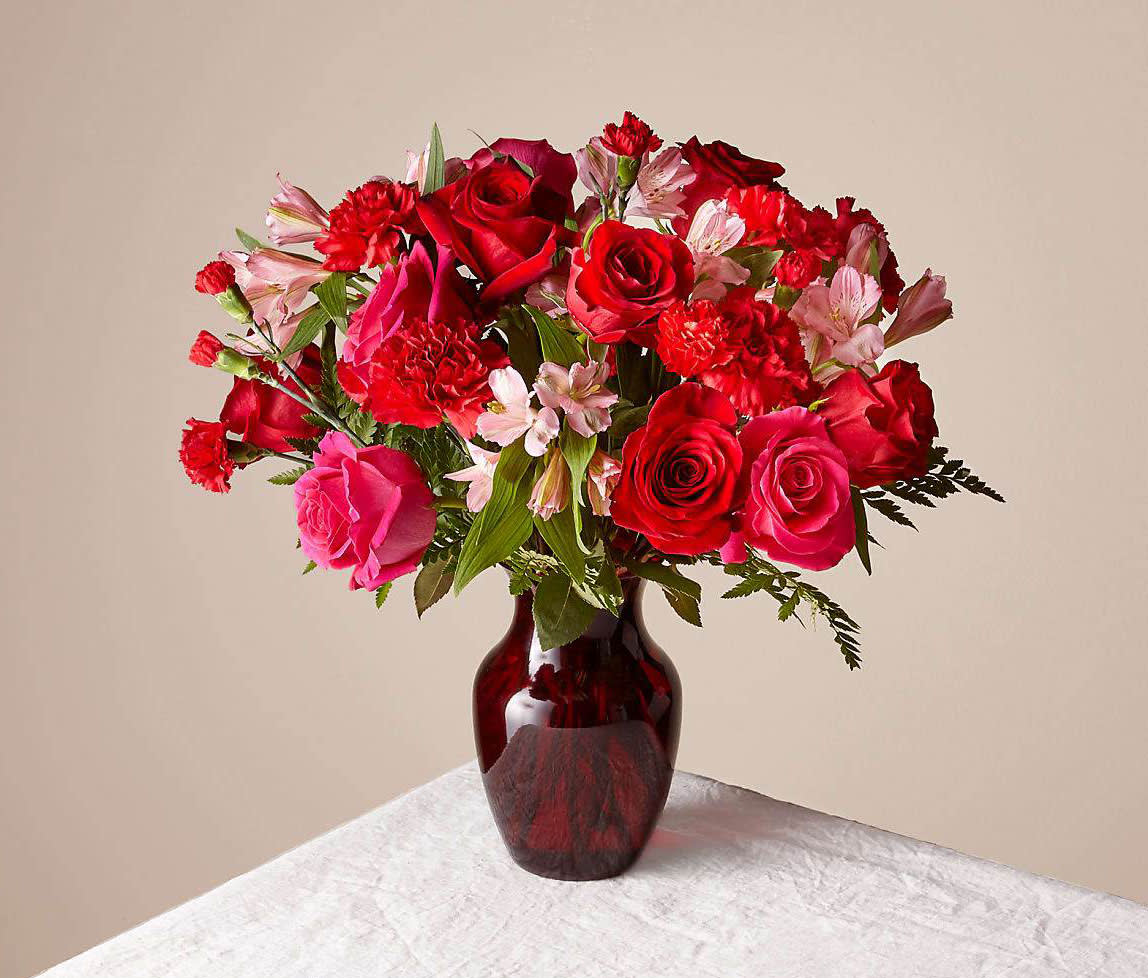 Red and pink rose bouquet in a dark glass vase
