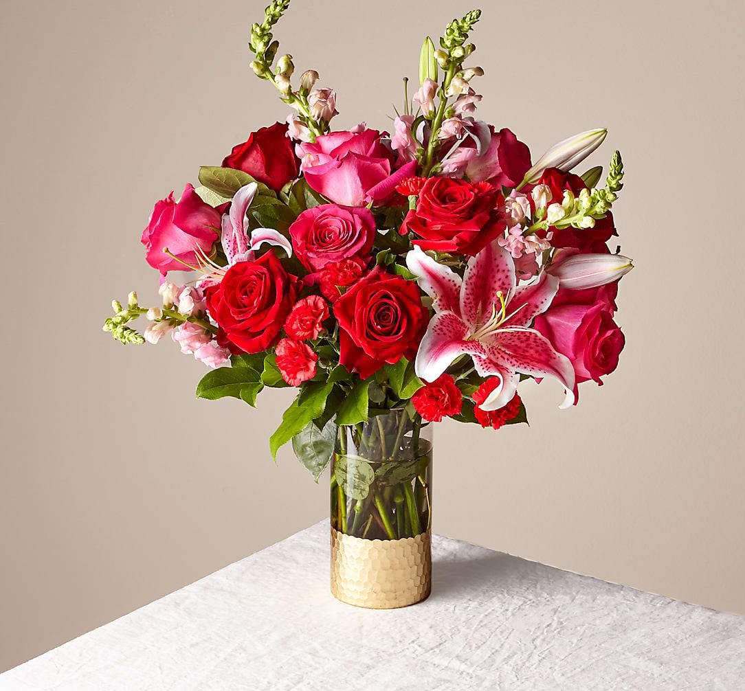 Bouquet of red and pink roses with lilies in a glass vase