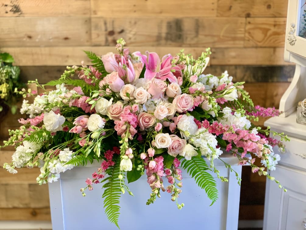 Large pink and white floral arrangement with roses and lilies on a white pedestal
