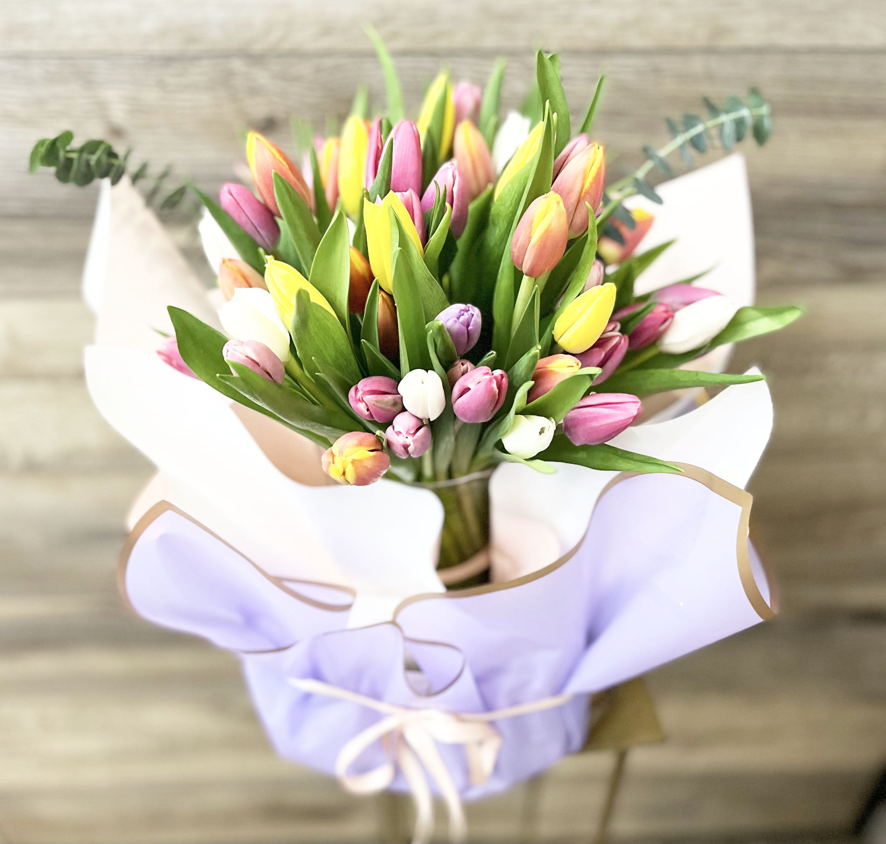 Bouquet of multicolored tulips wrapped in lavender paper