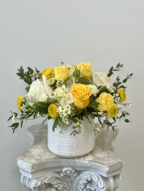 Yellow and white roses arranged in a white vase