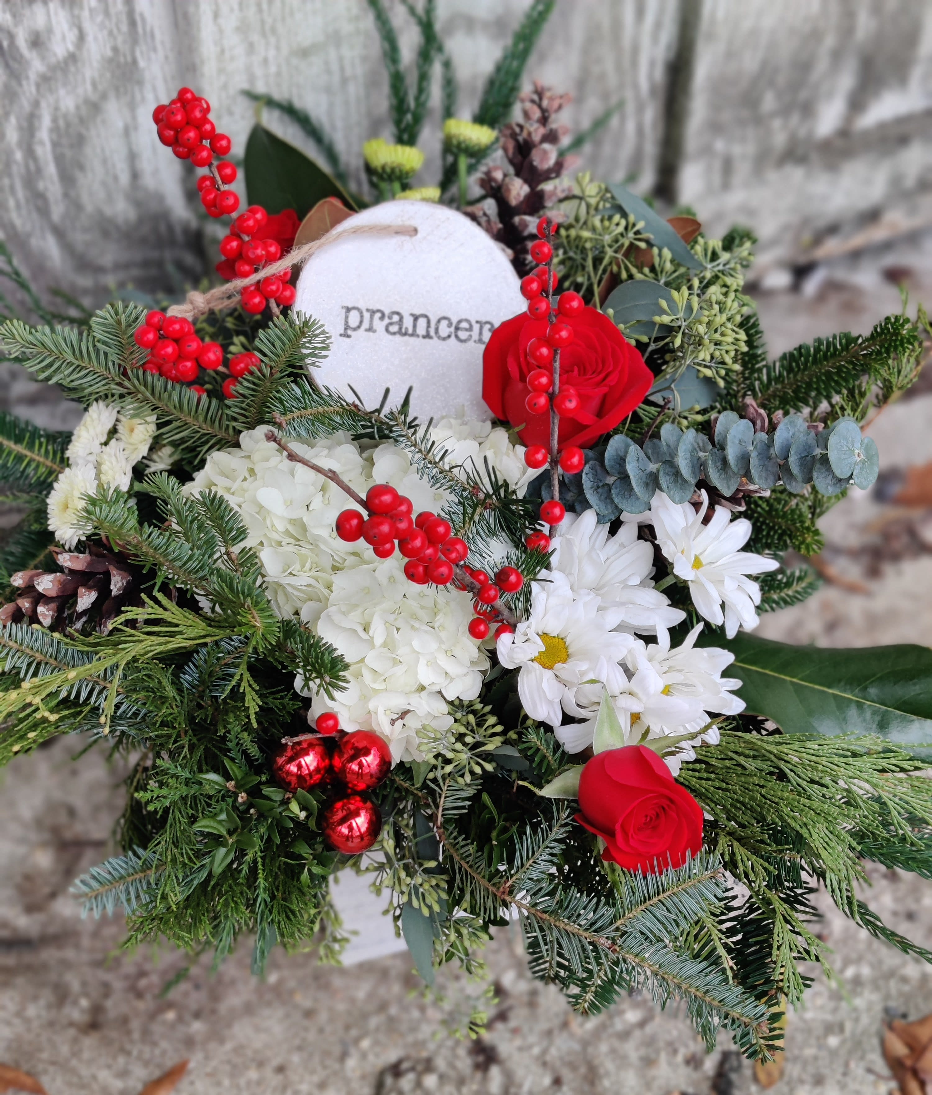 Red roses and white daisies in a festive winter bouquet with berries