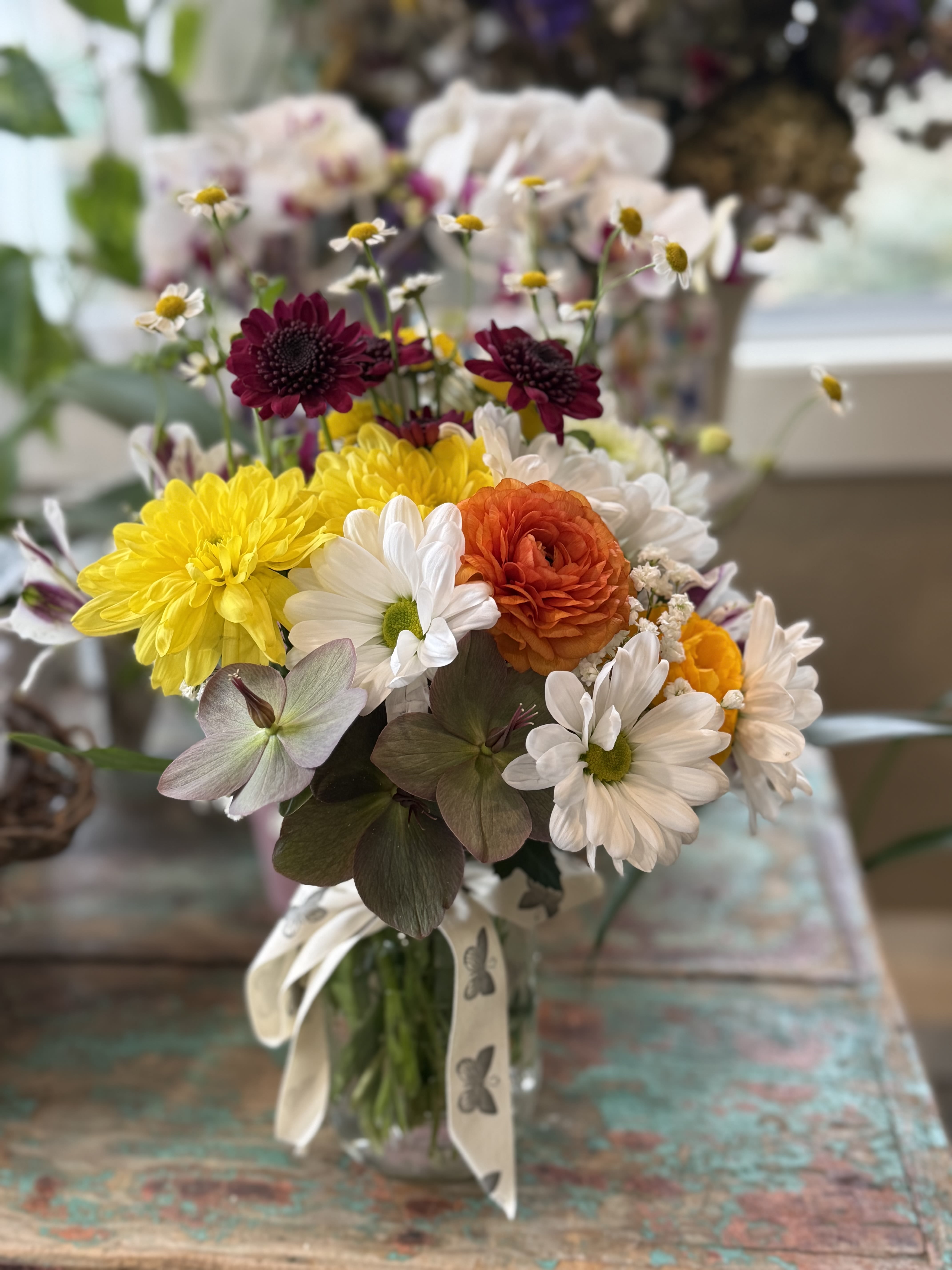 Mixed bouquet in a glass vase with yellow, white, orange, and burgundy blooms