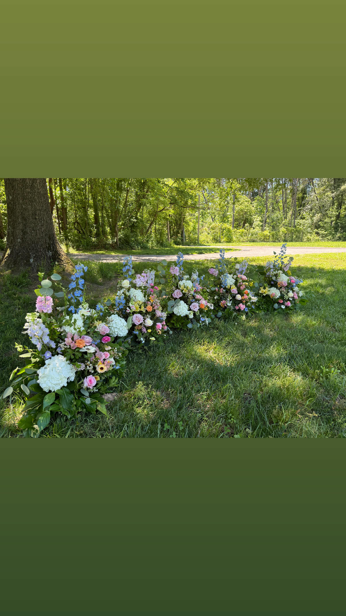 Low floral arrangements in pastel colors placed outdoors on grass