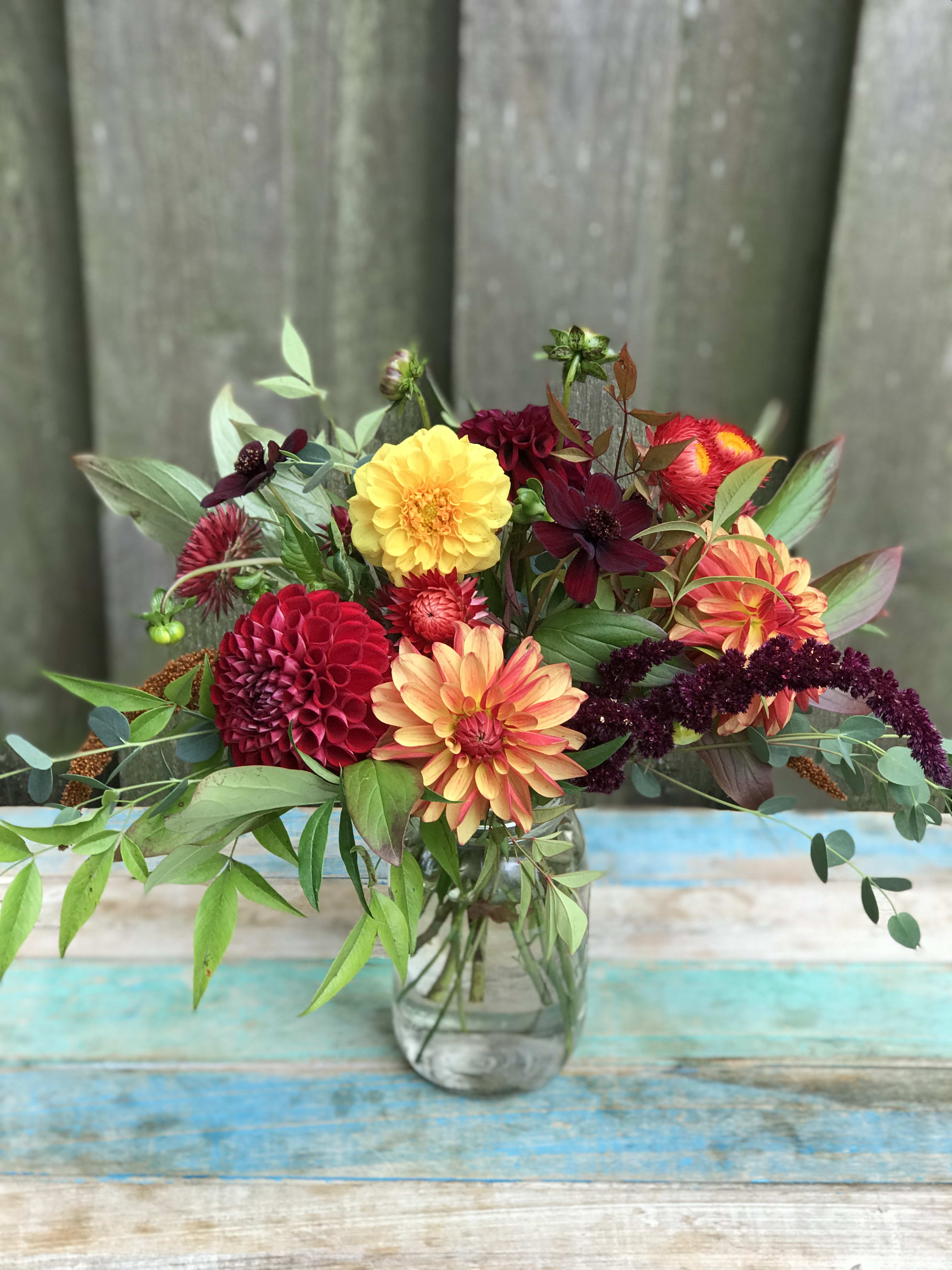Touch of Autumn  - A touch of seasonal colors gathered in a garden style mason jar design for a touch of Autumn. Blossoms vary based on availability.