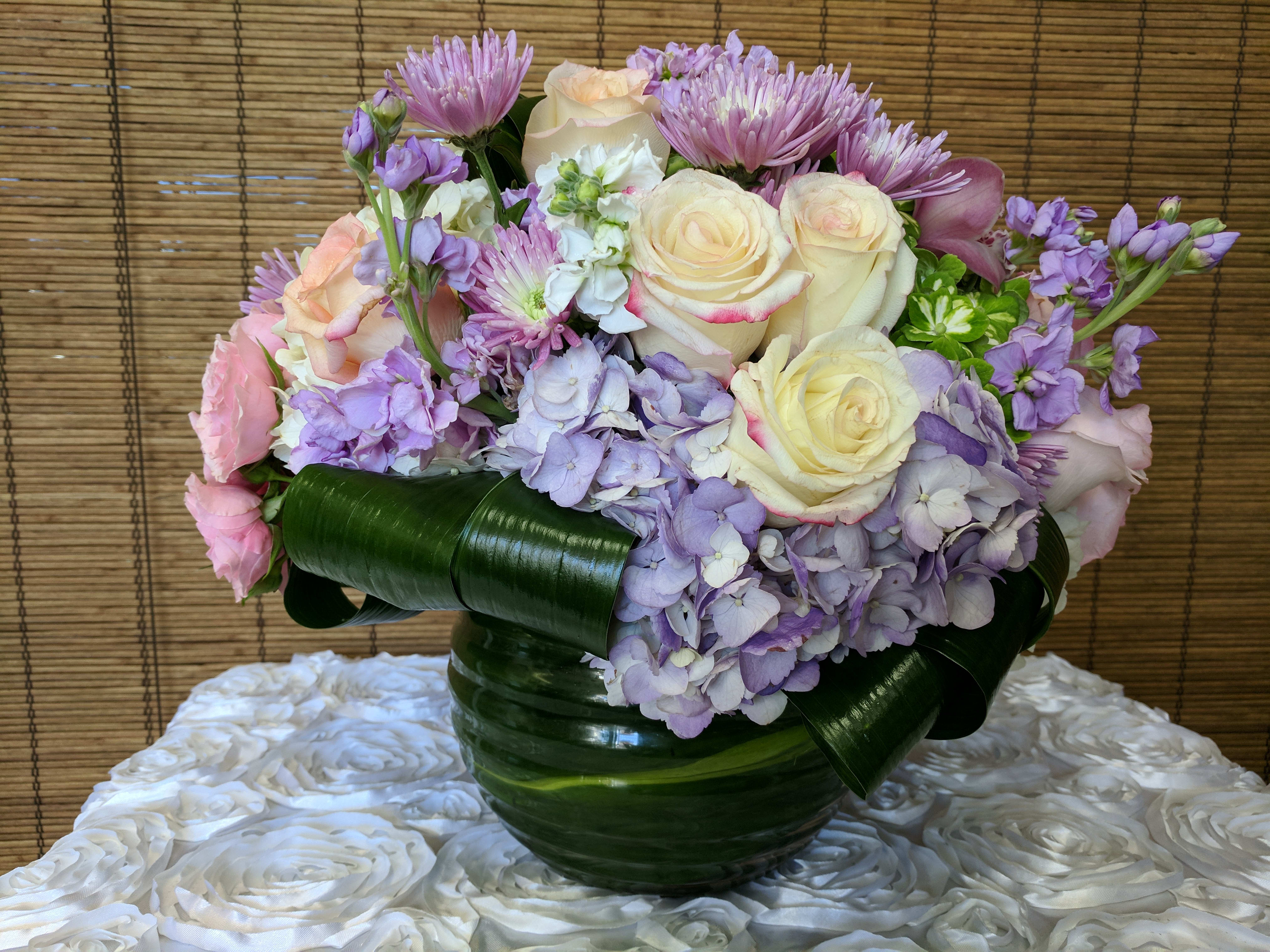 Subtle Elegance  - Lavender &amp; pink Hydrangea, white cream roses, lavender Cymbidium Orchids, Ti leaf accents with a Ti Leaf wrapped bubble bowl (Other color choices for the flowers can be selected as available - in a similar arrangement.)