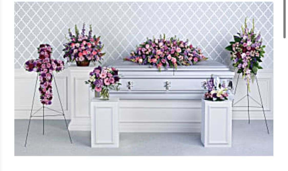 Pink and purple floral funeral casket spray with standing arrangements