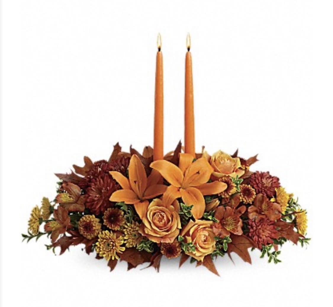 FAMILY GATHERING CENTERPIECE - A PERFECT CENTERPIECE FOR A FAMILY GATHERING. ORANGE ROSES, ASSIATIC LILIES, ORANGE ALSTROMERIAS, BUTTON POMPOMS, YELLOW AND RUST POMPOM, FALL FOLIAGE AND 2 TAPER ORANGE CANDLES.