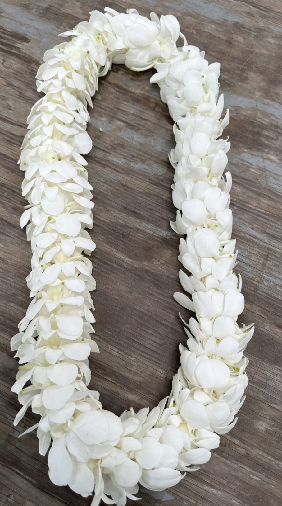 White flower lei laid in a U-shape on a wooden surface
