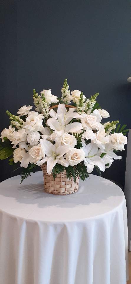 White lilies and roses arranged in a wicker basket