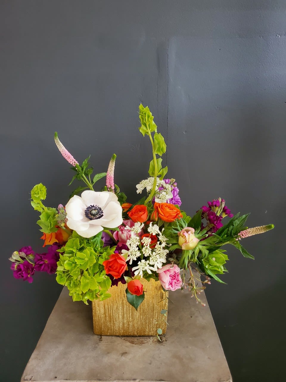 Colorful mixed flower arrangement in a gold square vase