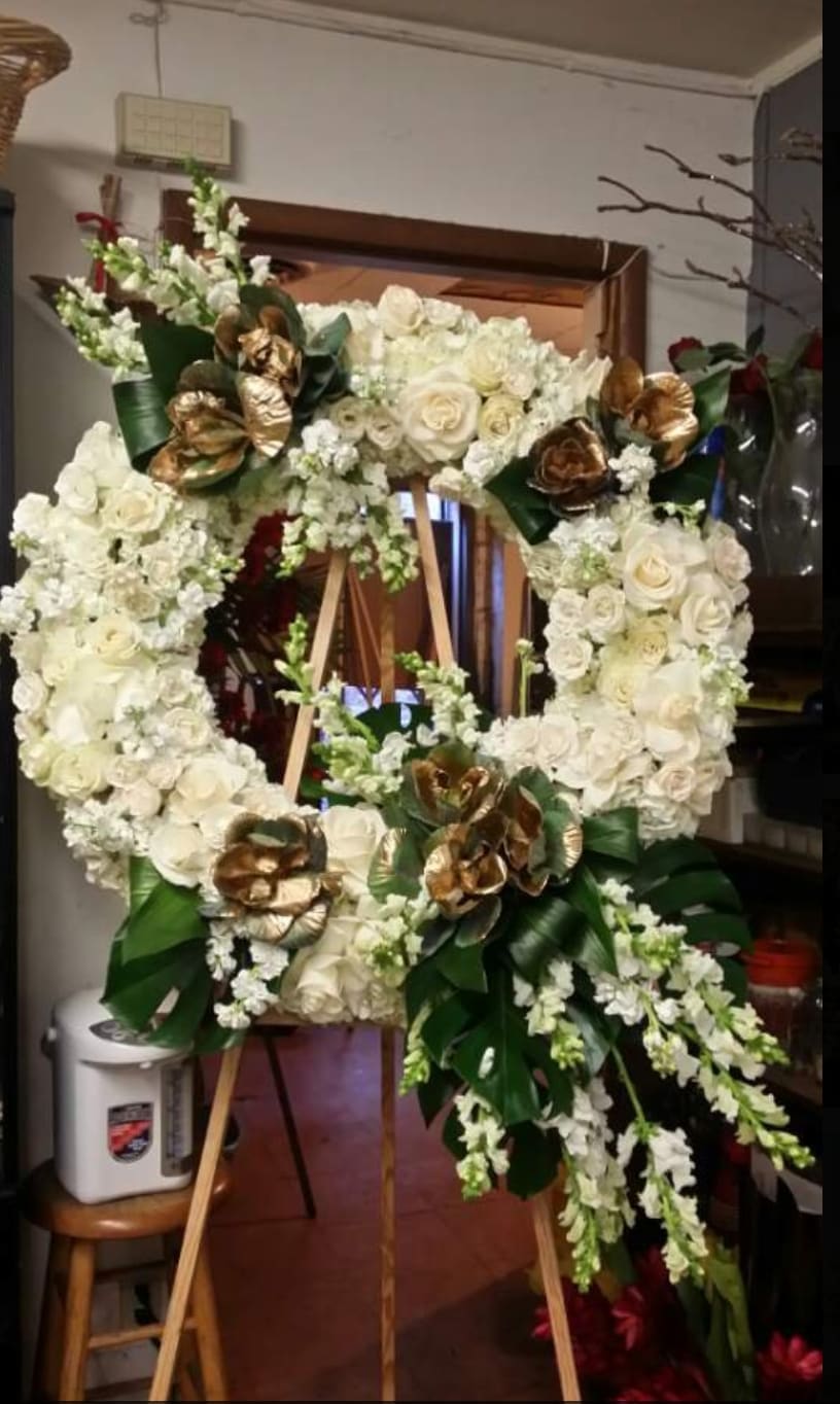 Large white floral wreath on a wooden easel with gold accents