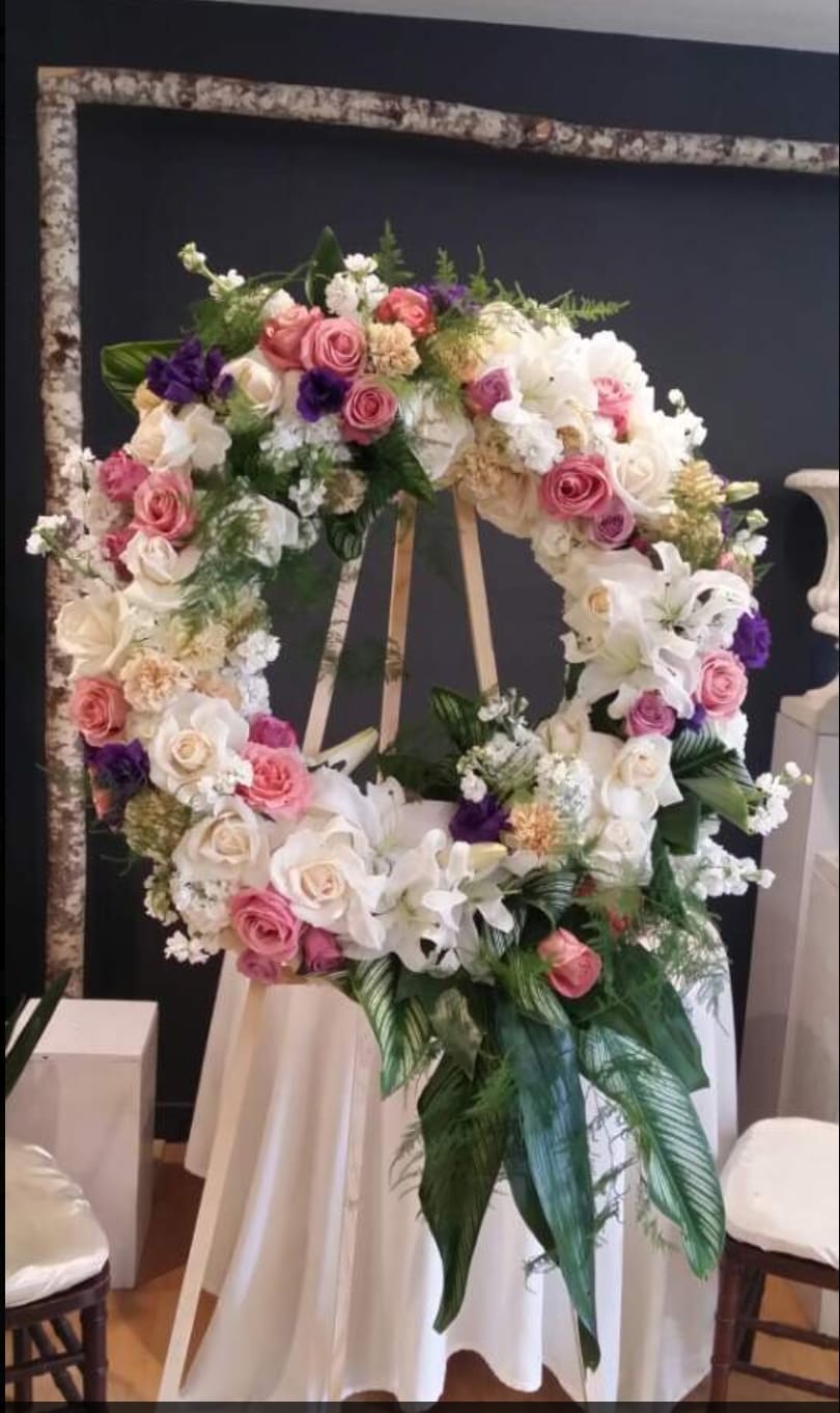 Large floral wreath on an easel with pink, white, and purple flowers