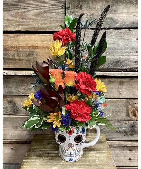 Day of the Dead Bouquet - Celebrate life and remembrance with our Day of the Dead Bouquet, a vibrant and artistic floral arrangement that honors tradition with color and joy. Designed in a festive ceramic sugar skull mug, this unique piece features bold colorful fall flowers and Foliage — perfectly capturing the spirit of Día de los Muertos. This eye-catching bouquet makes a striking centerpiece or gift for anyone who appreciates color, creativity, and cultural beauty. Each arrangement is handcrafted by our local florist in Omaha Metro area, ensuring freshness and one-of-a-kind artistry. Perfect for: Día de los Muertos celebrations Autumn home décor Unique gifts for friends and family Collectible keepsake mug