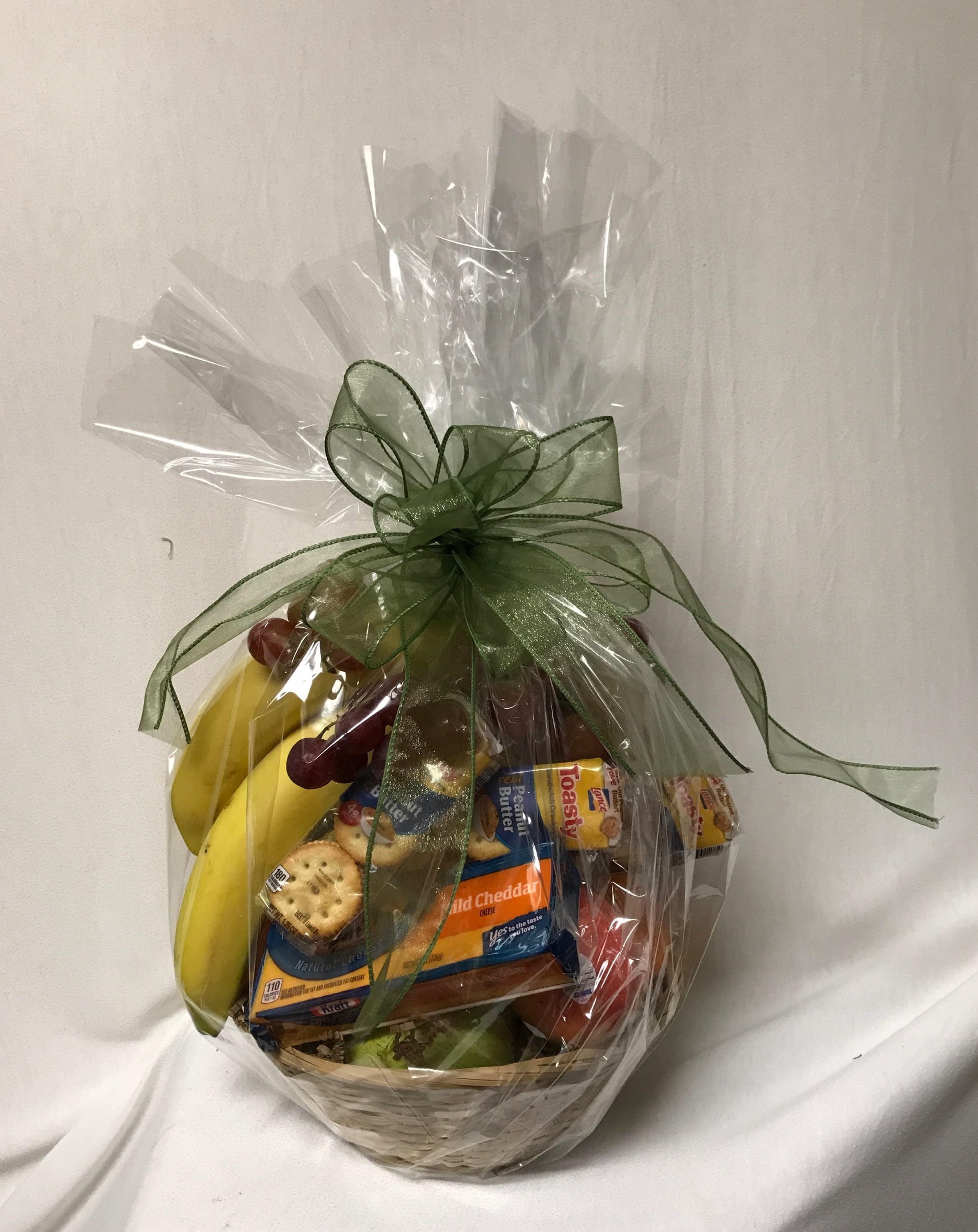 Gift basket with fruit and packaged snacks wrapped in clear cellophane