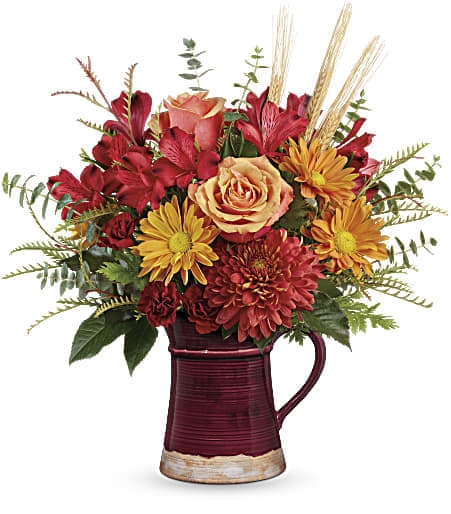 Fields Of Fall Bouquet - TF - Pour on the autumnal charm! A magnificent fall rose bouquet bursts beautifully from this hand-glazed ceramic pitcher, a food-safe gift in classic crimson that's sure to be a favorite vase and serving piece! Orange roses, red alstroemeria, miniature carnations and chrysanthemums are arranged with lush greens. Delivered in a Fall Pitcher.