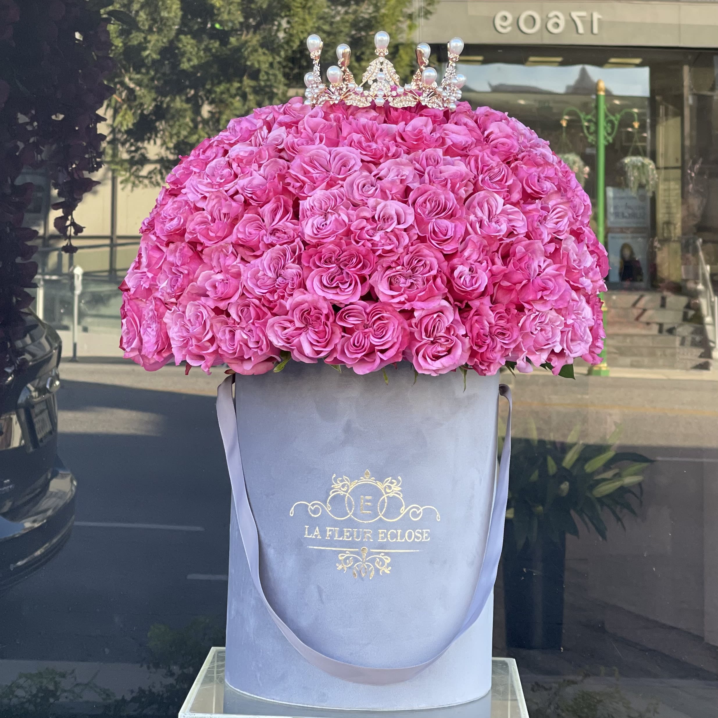 Large pink rose arrangement in a tall round box with a jeweled crown