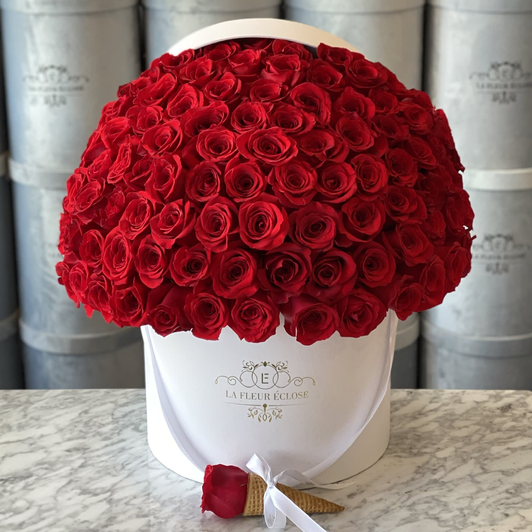 Large bouquet of red roses in a white hat box with a single rose boutonniere
