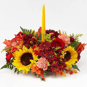 Giving Thanks Centerpiece - Fall colored flowers made into a round centerpiece with a gold candle.